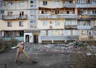 Um residente limpa uma área em um local de um prédio de apartamentos atingido por uma greve de drones russos